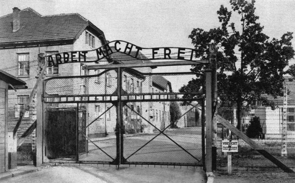 Portail de l’entrée principale d’Auschwitz-I , le “camp souche” : « ARBEIT MACHT FREI » (le travail rend libre).  Carte postale. Collection mémoire Vive. Photo : Stanislas Mucha.