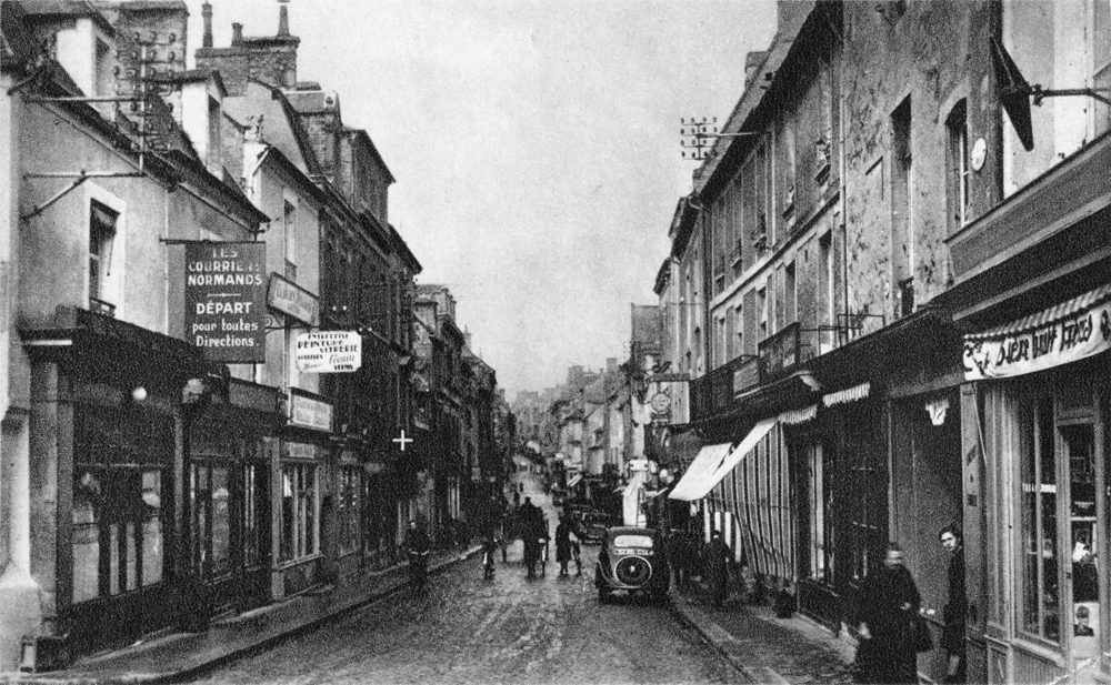 À gauche, succursale des Courriers Normands, rue Saint-Jean à Bayeux. Carte postale. Collection Mémoire Vive.