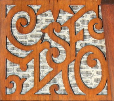 Grille en bois ajourée dessinant le signe COTSF protégeant le haut-parleur d’un poste-radio.
