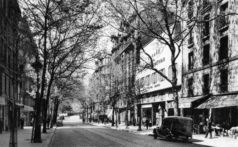 Paris, l’avenue Simon Bolivar dans les années 1930. Au fond, une des entrées hautes du jardin des Buttes Chaumont. L’entrée de l’immeuble du n° 21 est située sur le trottoir de gauche, invisible sur la photo, mais à située à hauteur du premier arbre… Carte postale, collection Mémoire Vive.