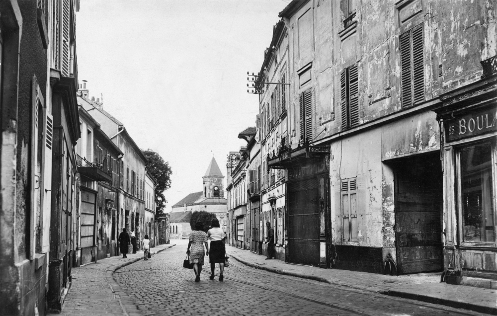     Romainville. La rue de Paris. La boucherie visible à droite est située au n° 21.     Carte postale oblitérée en 1947. Collection Mémoire Vive.