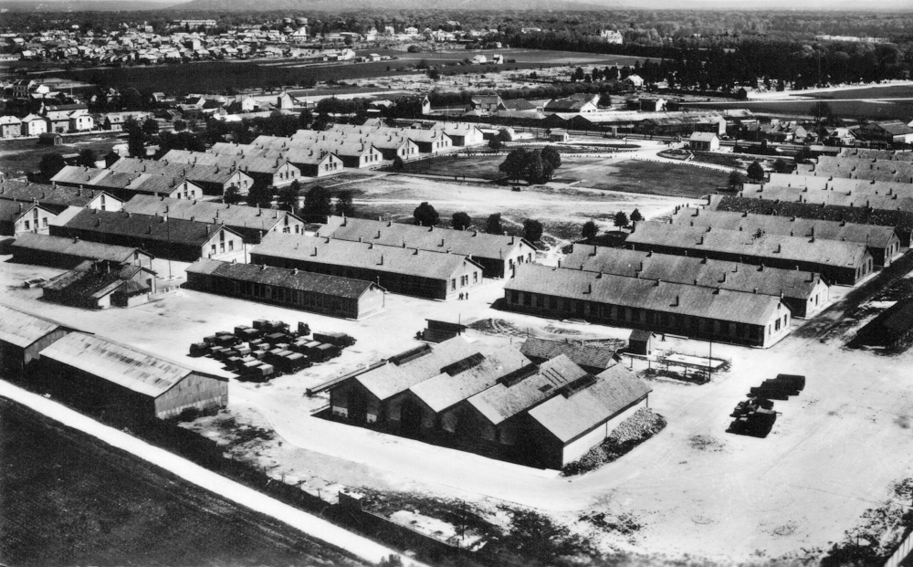 La caserne de Royallieu en 1957 ; au deuxième plan, les six grands bâtiments alignés du quartier C.     L’enceinte et les miradors du camp ont disparu (les deux hangars en bas à gauche n’existaient pas). Carte postale. Coll. Mémoire Vive.