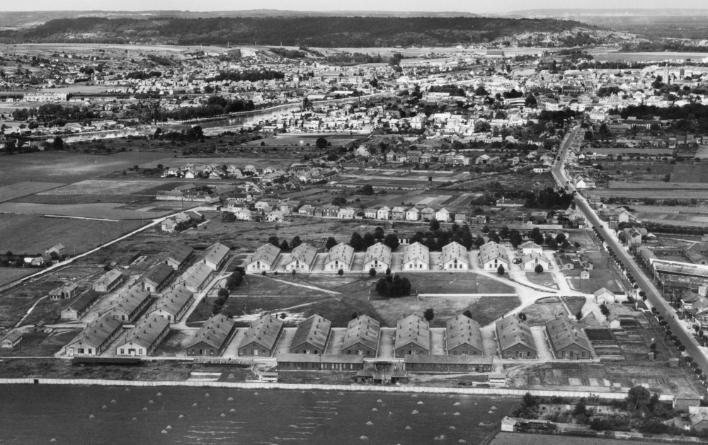 Le camp militaire de Royallieu en 1956. Au premier plan, en partant de la droite, les huit bâtiments du secteur A : « le camp des communistes ». En arrière-plan, la ville de Compiègne. Carte postale, coll. Mémoire Vive.